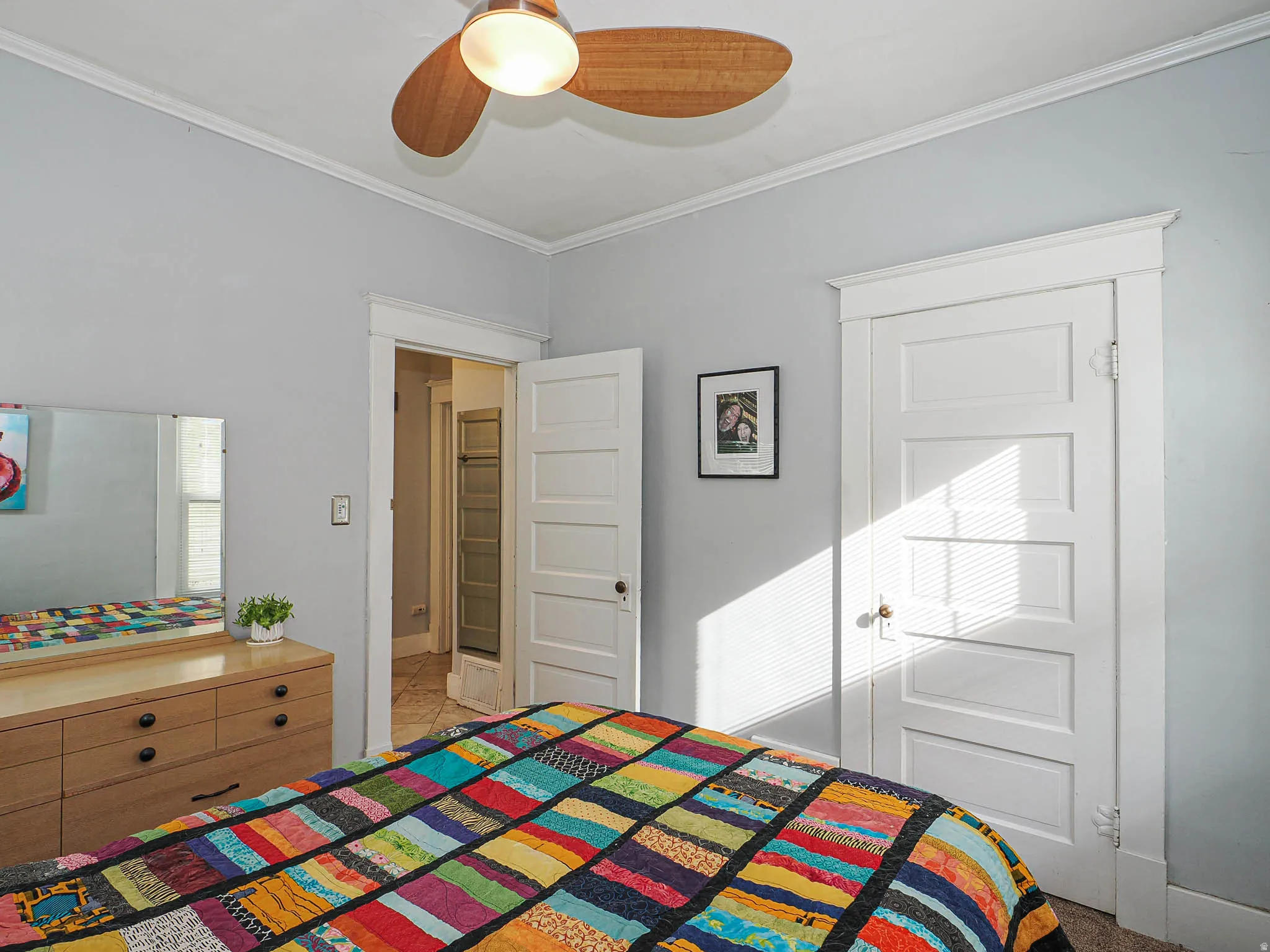 Ceiling fan with wooden blades, crown molding, and a solid five-panel interior door
