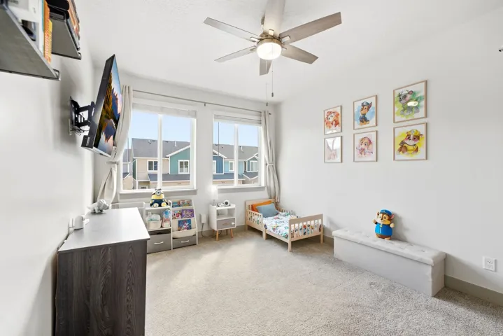 Recessed lighting, ceiling fan with integrated light, dual windows, wall-mounted television, and neutral carpeting