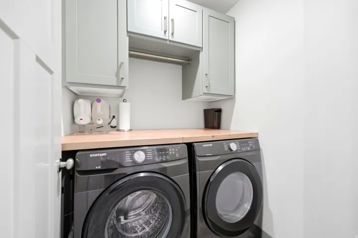 Light-toned wall cabinets with brushed nickel hardware, light wood-finish countertop, and white walls