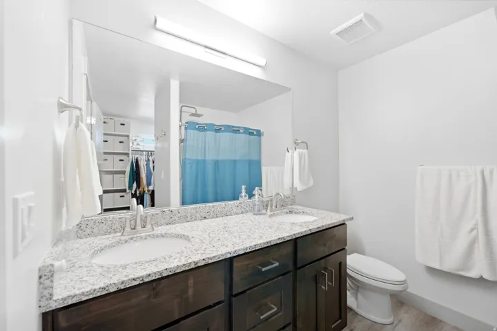 Dual vanity with light-toned granite countertop, dark wood-finish cabinetry, and undermount sinks