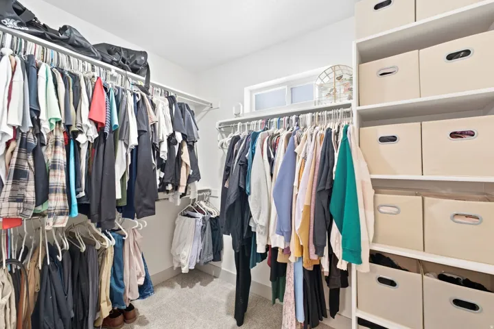 Walk-in closet featuring built-in shelving, multiple hanging rods, and a high window
