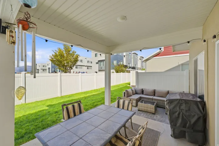 Covered patio with a tiled dining surface, string lighting, and a fenced yard