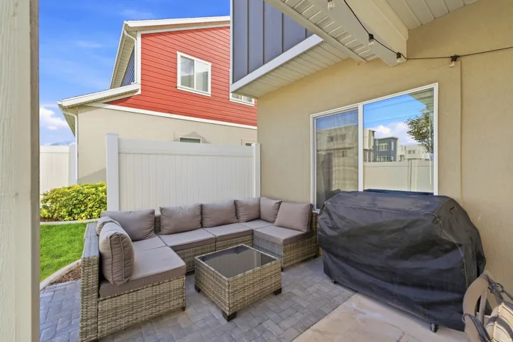 Paved patio area with a privacy fence, an exterior window, and a soffit ceiling