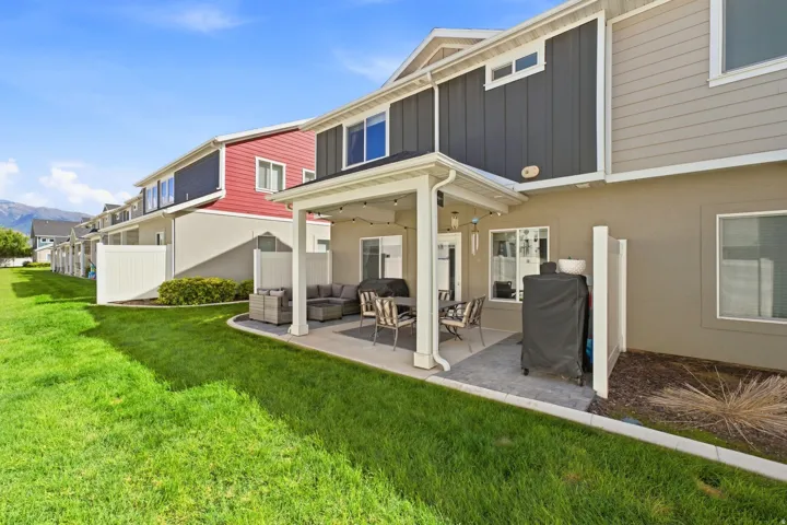 Paved patio area with a covered pergola, exterior lighting, and a privacy fence
