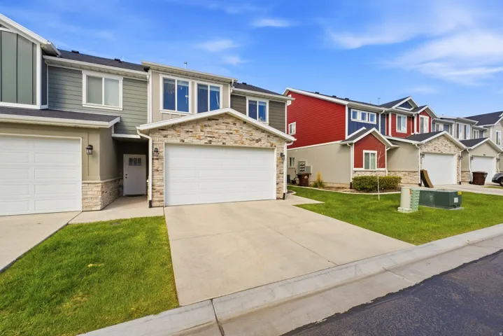 Townhome exterior featuring stone accents, a two-car garage, and a concrete driveway