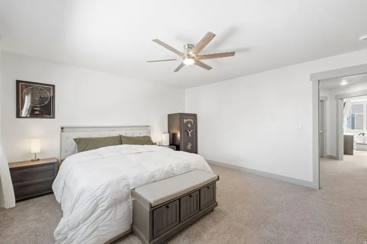Neutral tone wall paint, vaulted ceiling, ceiling fan with integrated lighting, and carpeted flooring