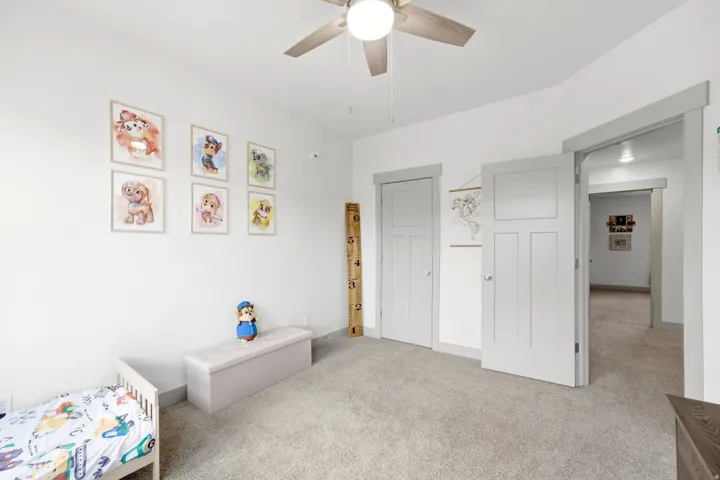 Neutral wall paint, light gray carpeting, and a ceiling fan with integrated lighting