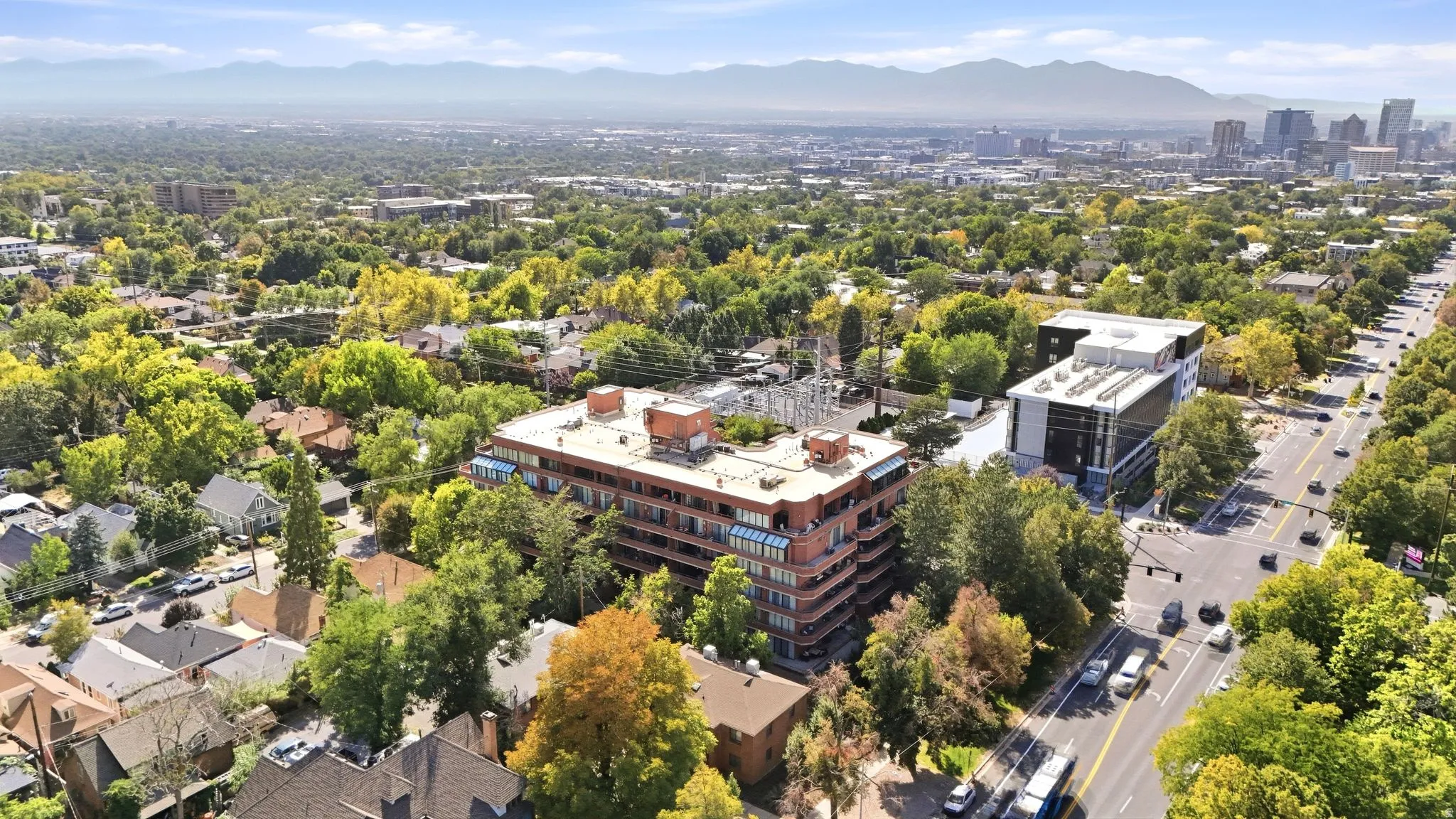 Aerial perspective of an urban setting with a multi-story building featuring multiple balconies and a flat roof