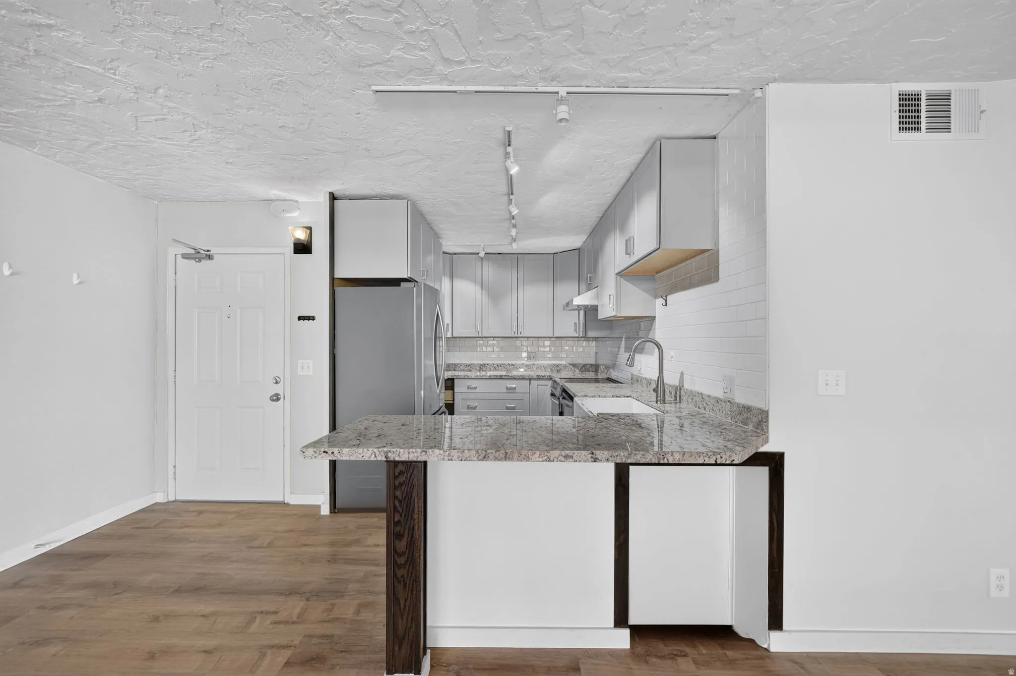 Kitchen featuring gray cabinetry, stainless steel appliances, granite countertops, and a subway tile backsplash