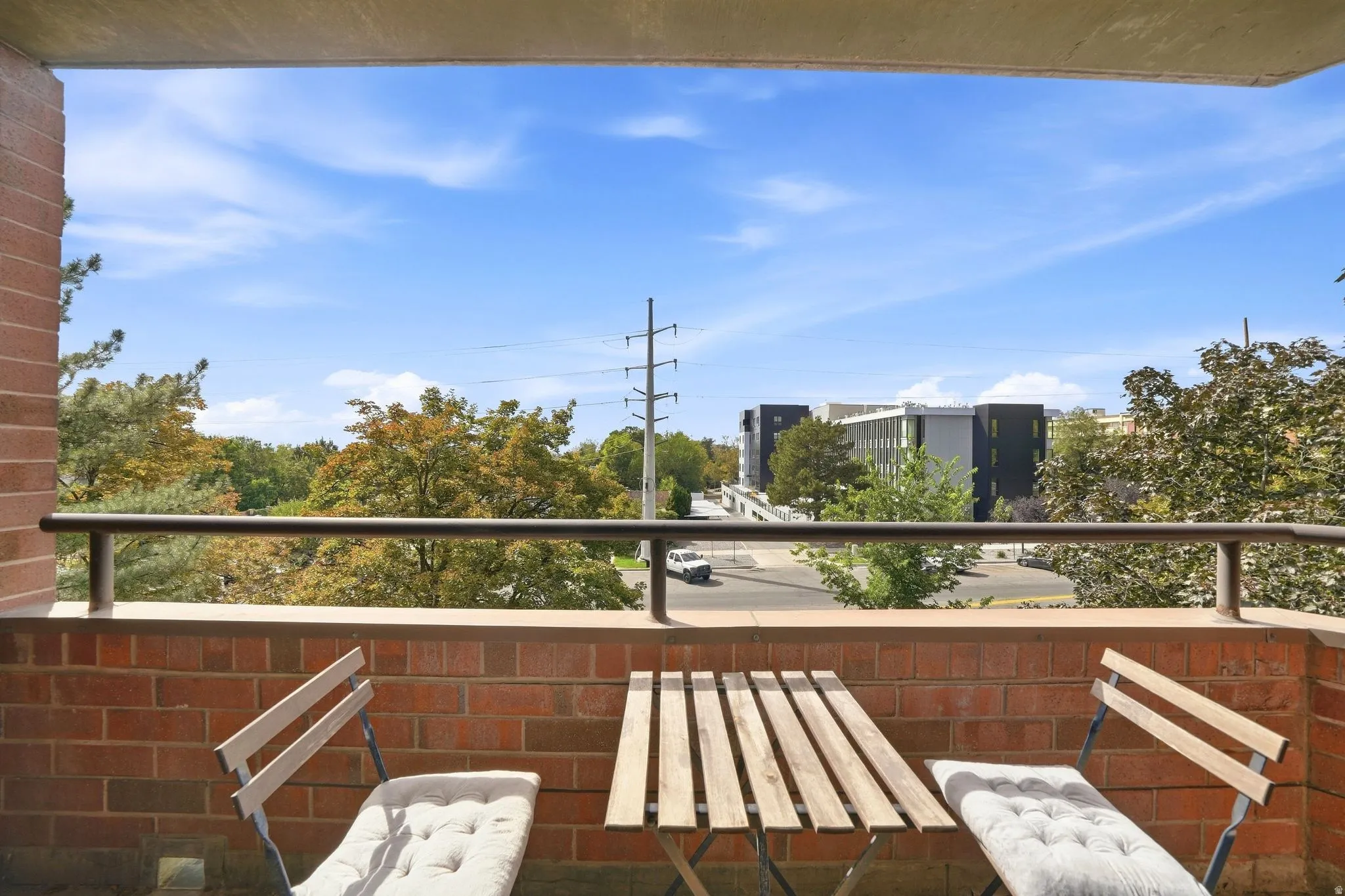 Balcony featuring a brick exterior wall and a metal railing