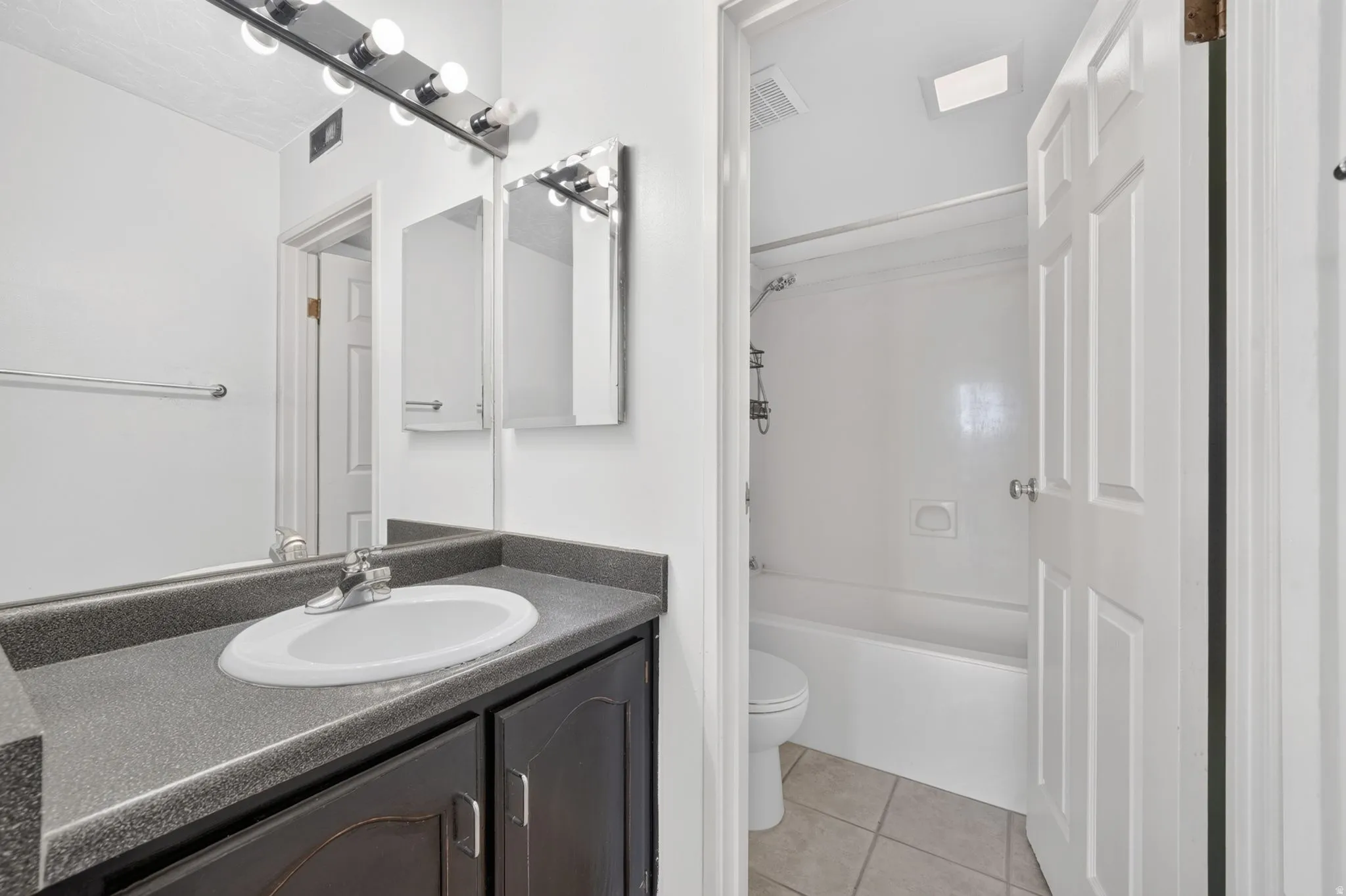 Vanity with a laminate countertop, integrated sink, and dark wood-finish cabinetry