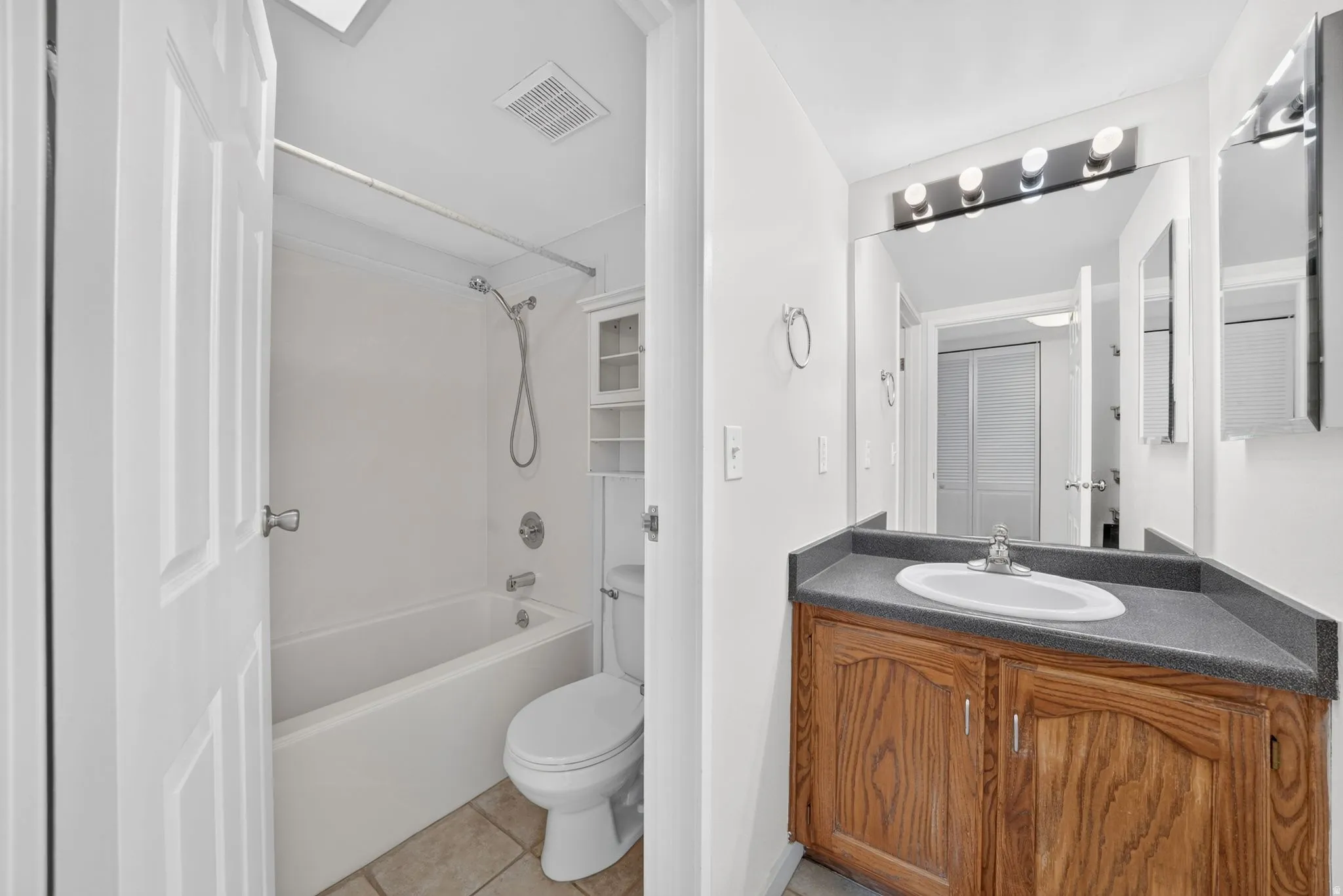 Bathroom featuring a vanity with a dark countertop, an undermount sink, and wood-finish cabinetry