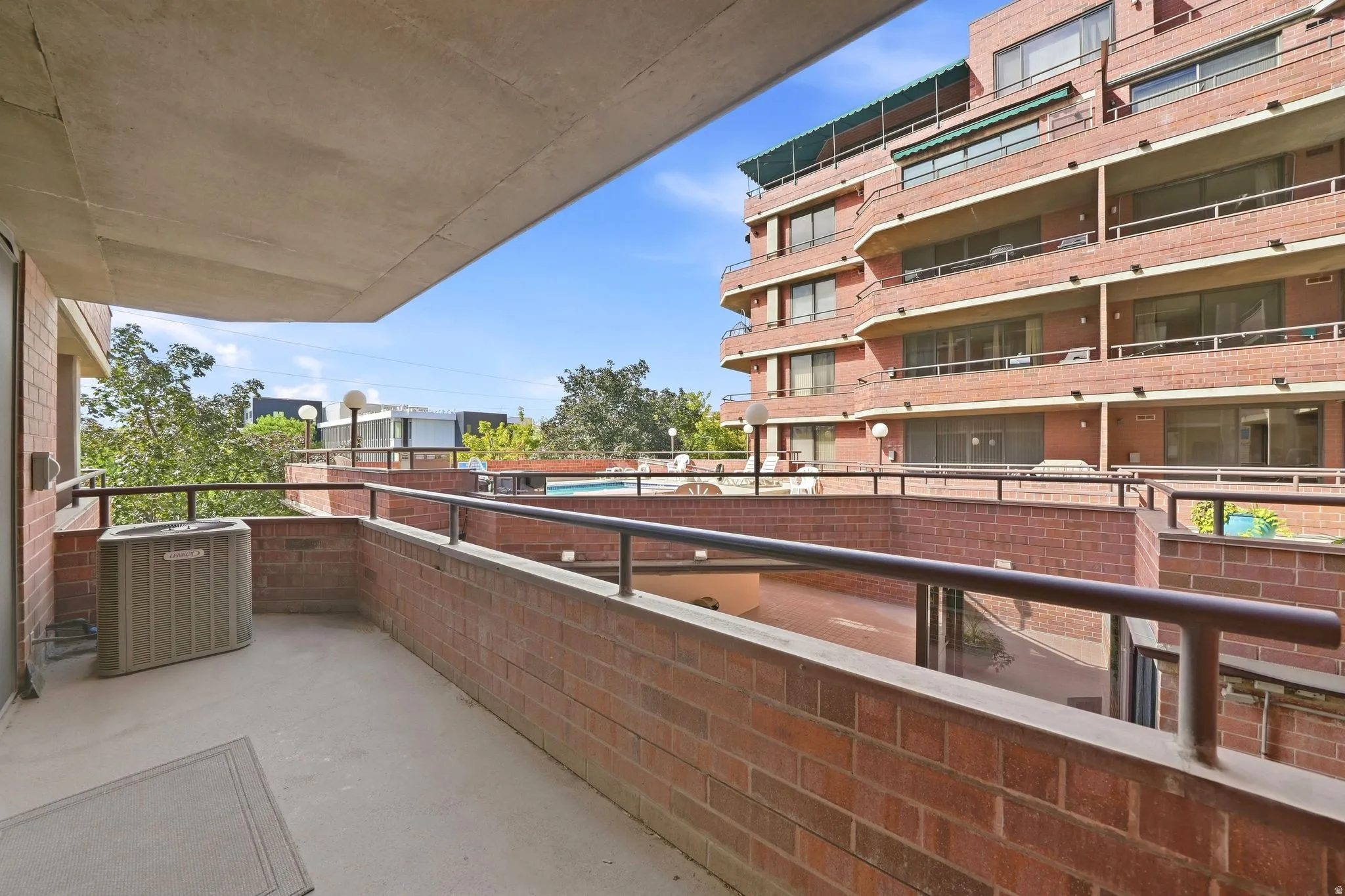 Balcony with concrete flooring and brick parapet walls, featuring metal railings