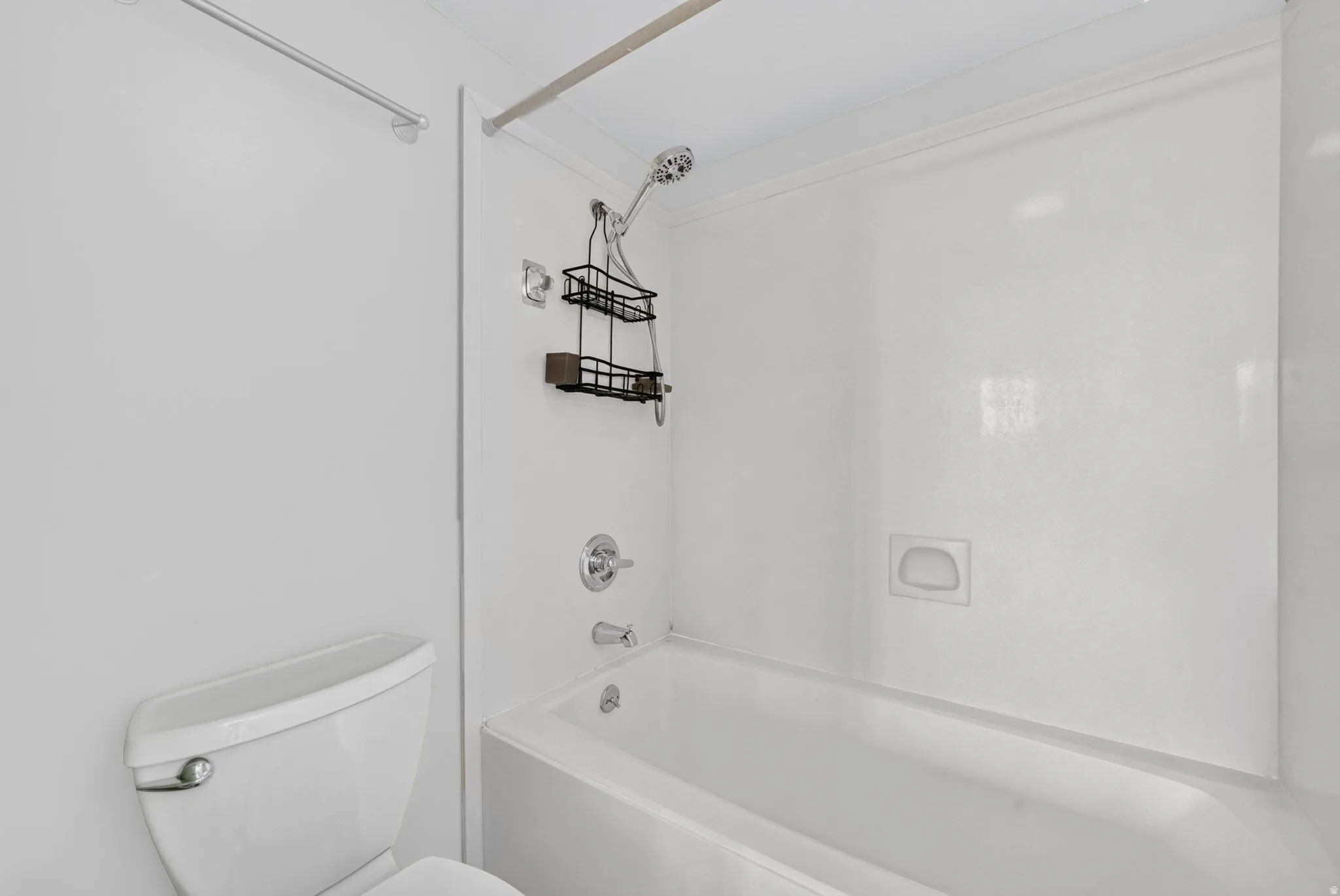 White acrylic shower surround with an integrated soap dish and chrome fixtures
