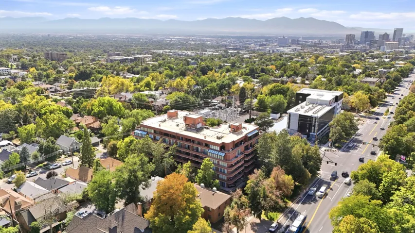 Aerial perspective of an urban setting with a multi-story building featuring multiple balconies and a flat roof