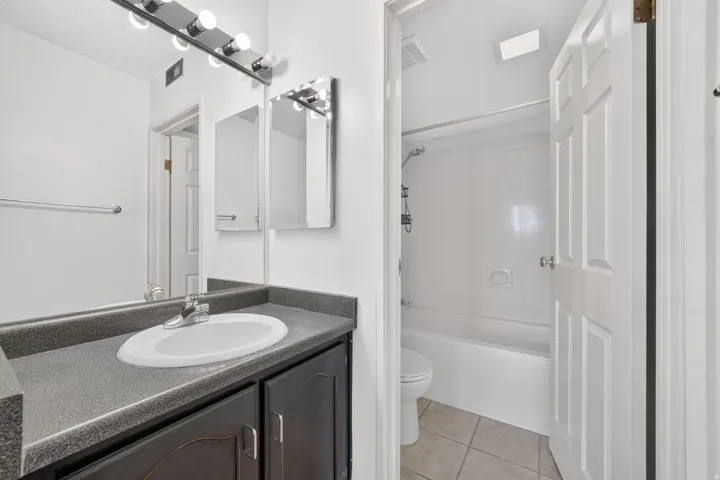 Vanity with a laminate countertop, integrated sink, and dark wood-finish cabinetry