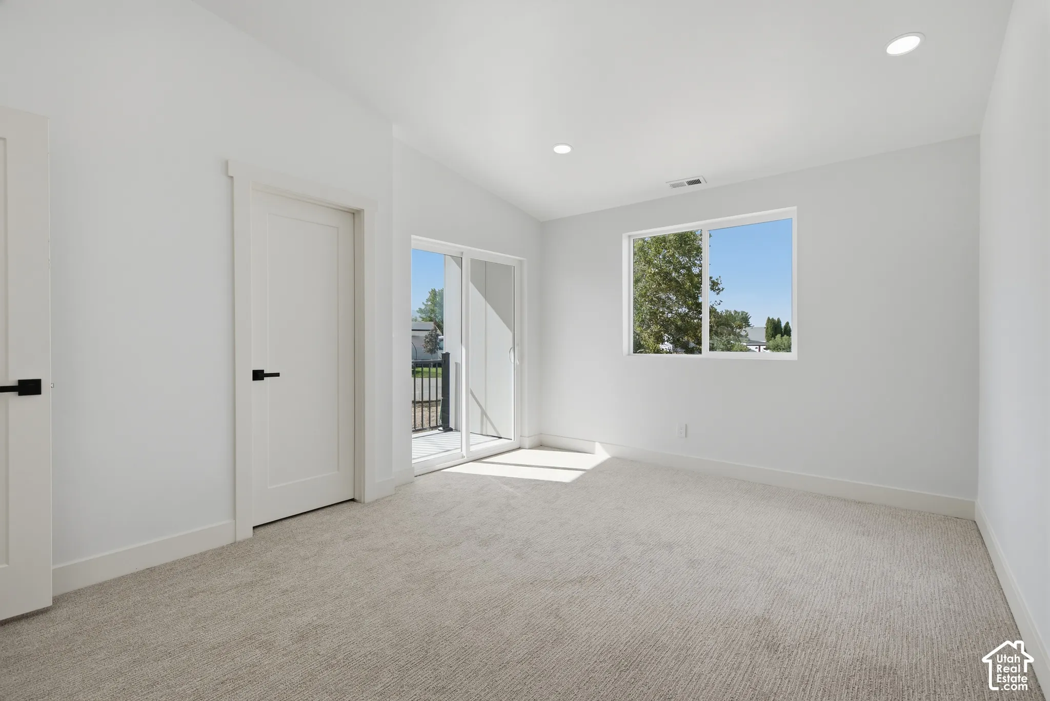 Vaulted ceiling, recessed lighting, white interior doors, sliding glass door, and neutral-toned carpet