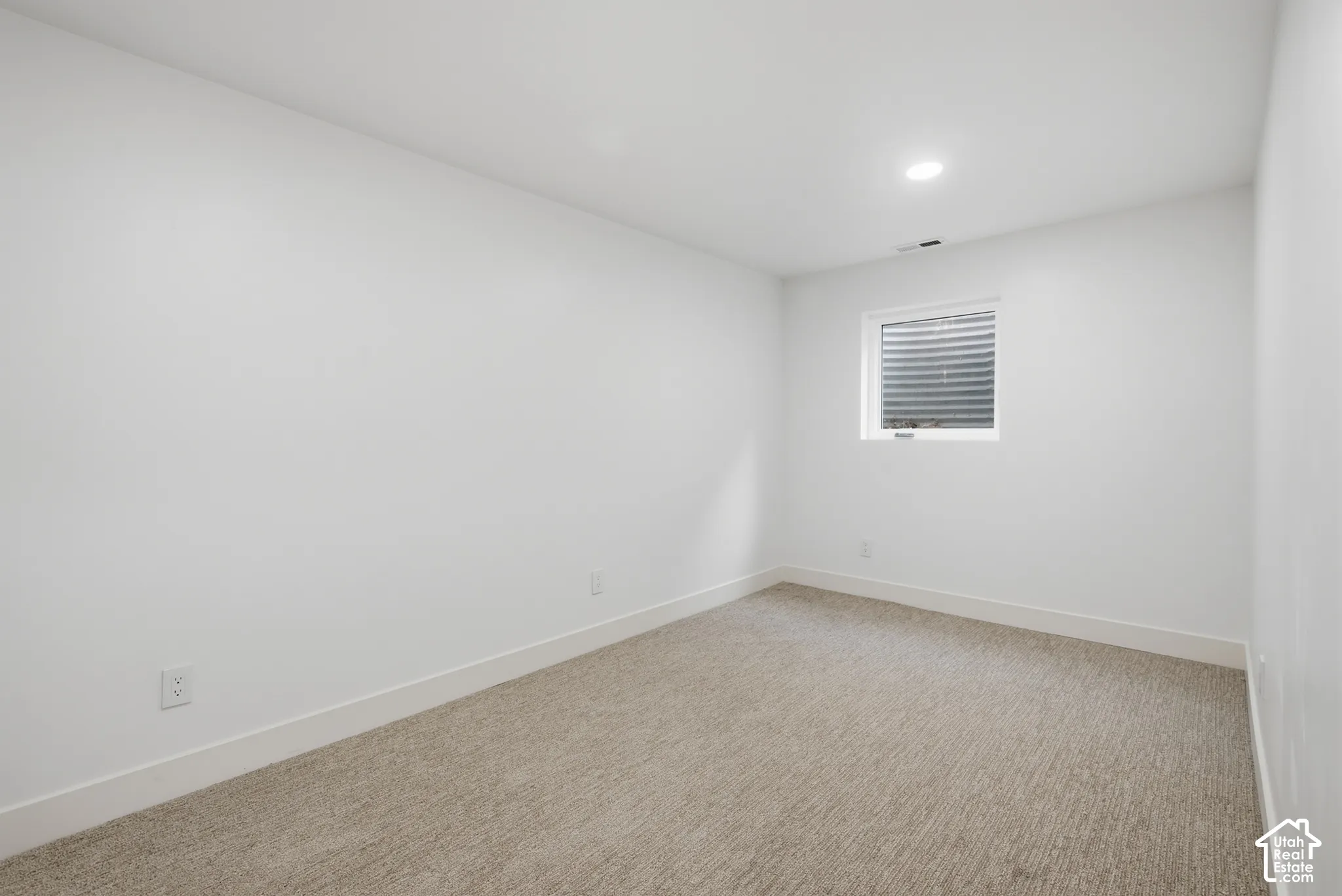 Neutral tone carpeting, recessed lighting, white walls, and a window with blinds
