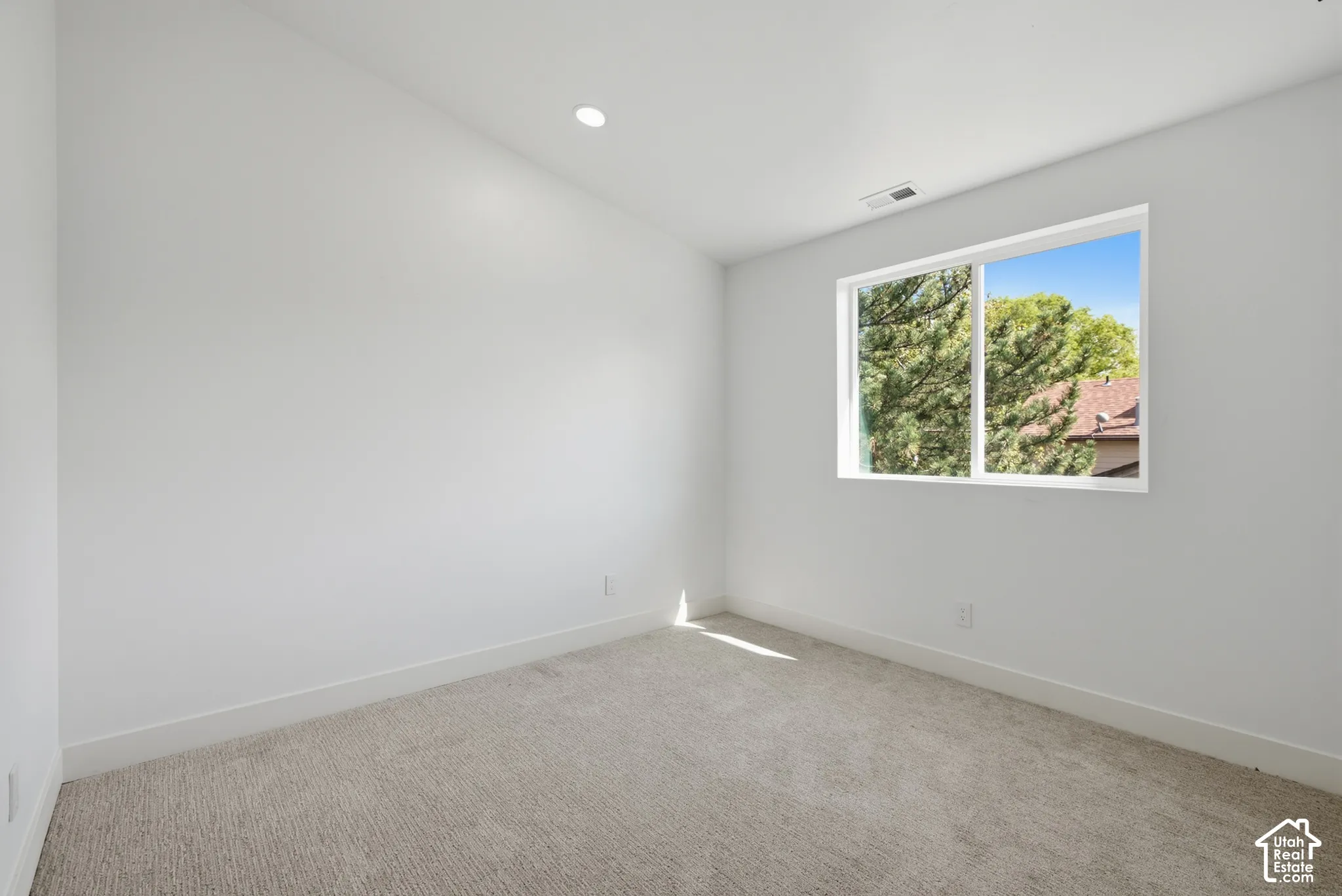 Recessed ceiling lighting, white walls, light-colored carpeting, and a window with white trim