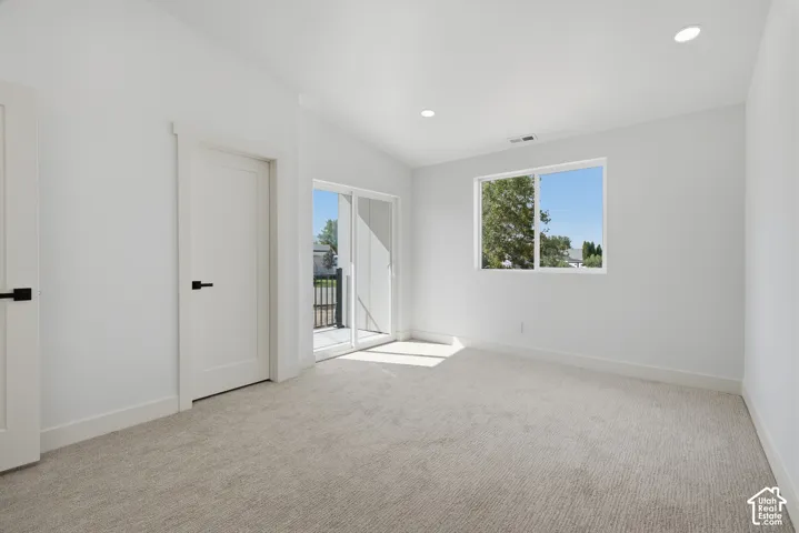Vaulted ceiling, recessed lighting, white interior doors, sliding glass door, and neutral-toned carpet