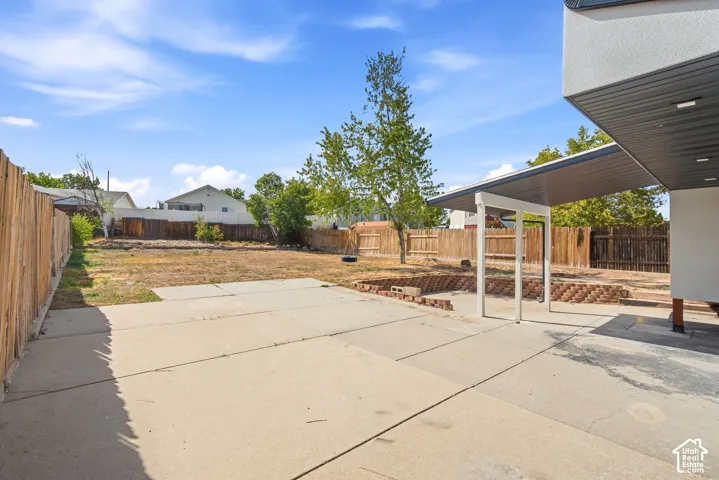 Expansive backyard with concrete patio, wood fencing, and a covered patio area