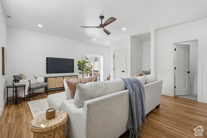 Wood-finish flooring, recessed lighting, and a ceiling fan enhance this living space