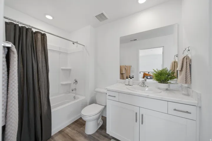 White vanity with a single basin sink and a stone-finish countertop