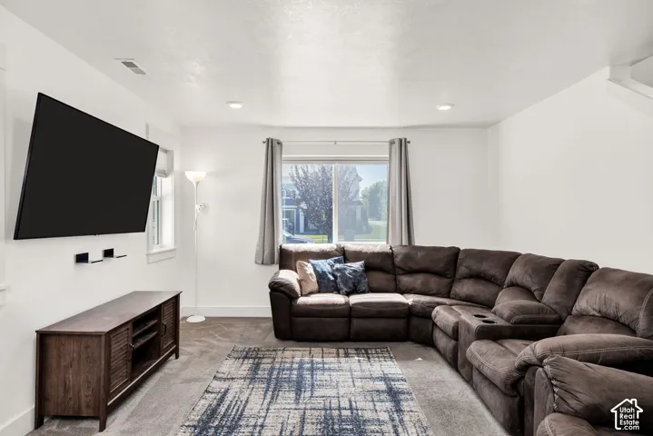 Carpeted living area with recessed lighting, a built-in media console, and natural light from a window