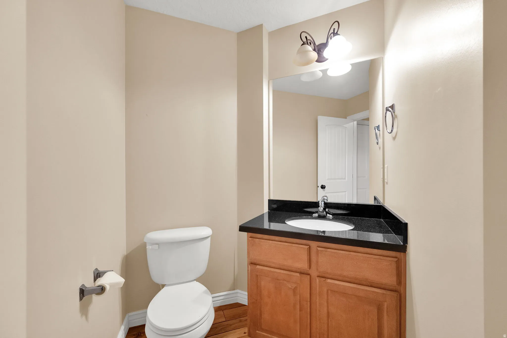 Wood-finish flooring with a light-colored vanity featuring a dark countertop and integrated sink