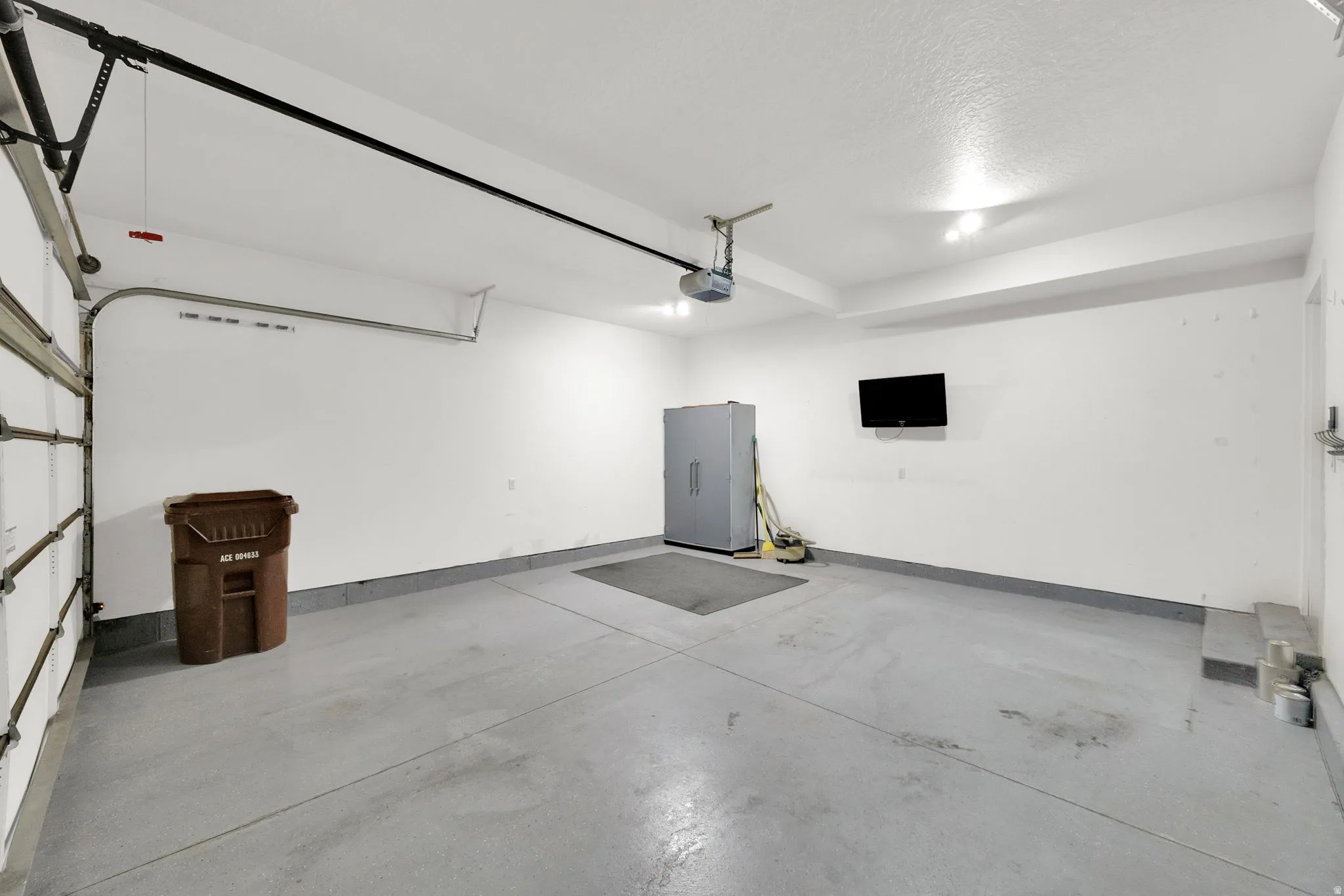 Attached garage with an automatic opener, finished walls, and overhead lighting
