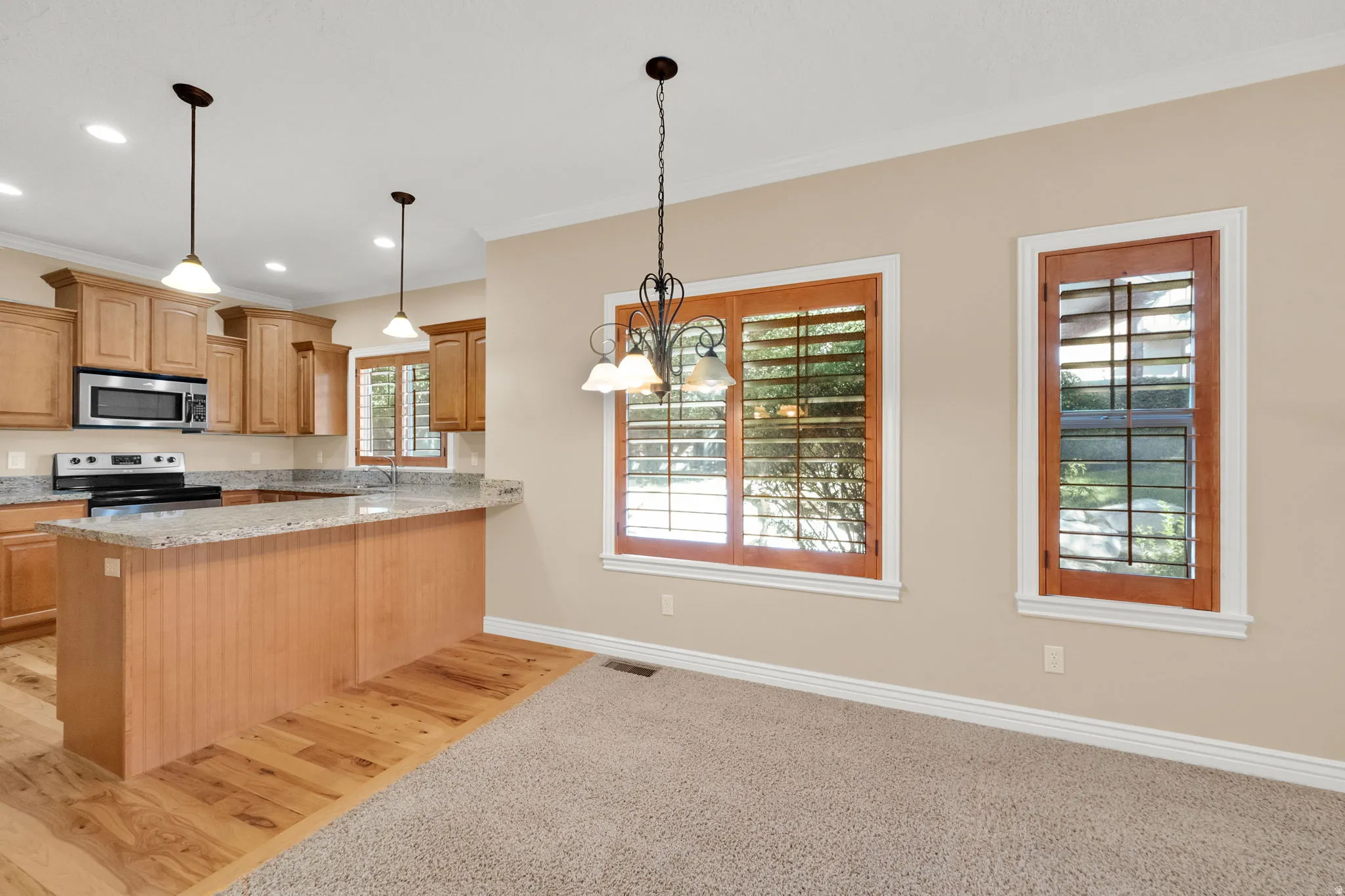 Kitchen island with beadboard paneling, light wood-finish cabinetry, stainless steel appliances, and light-toned countertops