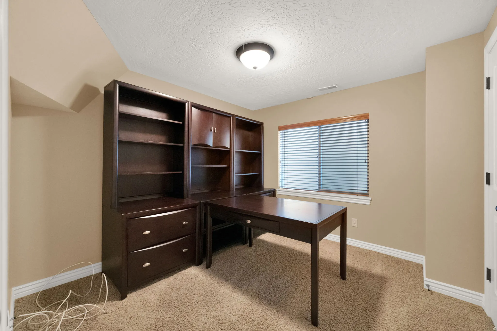Built-in cabinetry with desk, recessed window with wood trim, and a ceiling-mounted light fixture