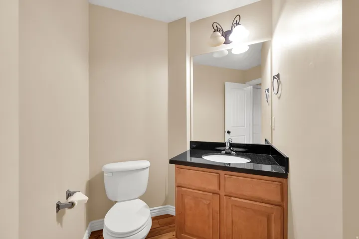 Wood-finish flooring with a light-colored vanity featuring a dark countertop and integrated sink