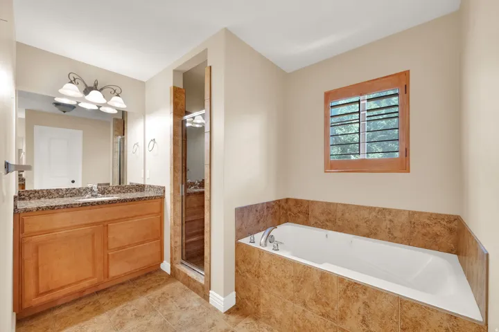 Vanity with a granite-style countertop, undermount sink, and wood-finish cabinetry