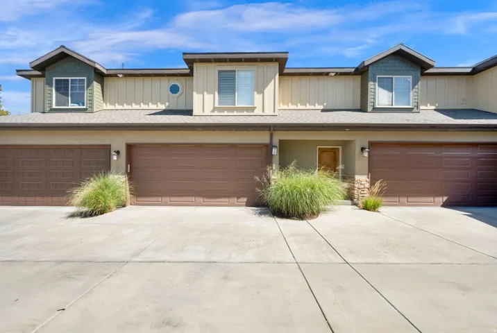 Multi-level facade with wood-finish garage doors, concrete driveway, and stone accents