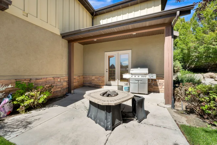 Covered patio with a stone fire pit, textured stucco exterior, and stone veneer accents