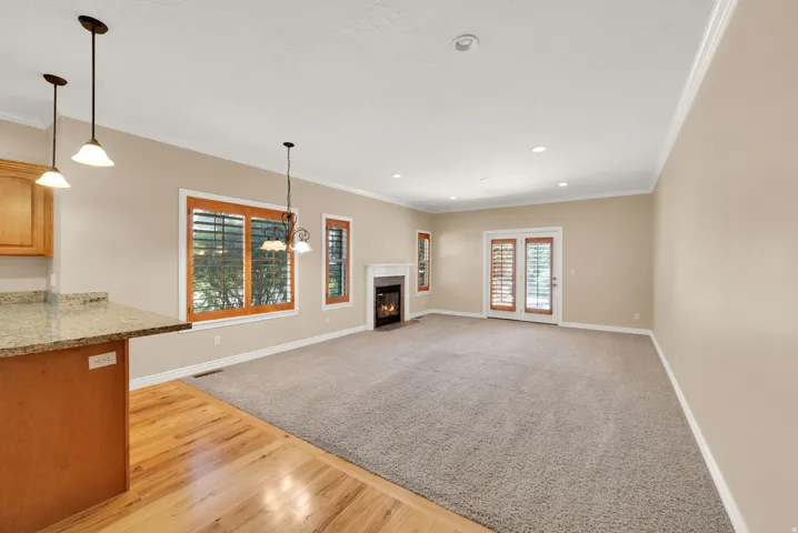 Open-concept living area with a built-in fireplace, crown molding, recessed lighting, and wood-frame French doors