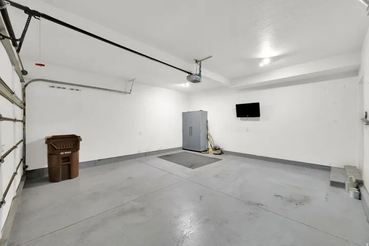 Attached garage with an automatic opener, finished walls, and overhead lighting