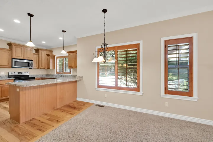 Kitchen island with beadboard paneling, light wood-finish cabinetry, stainless steel appliances, and light-toned countertops
