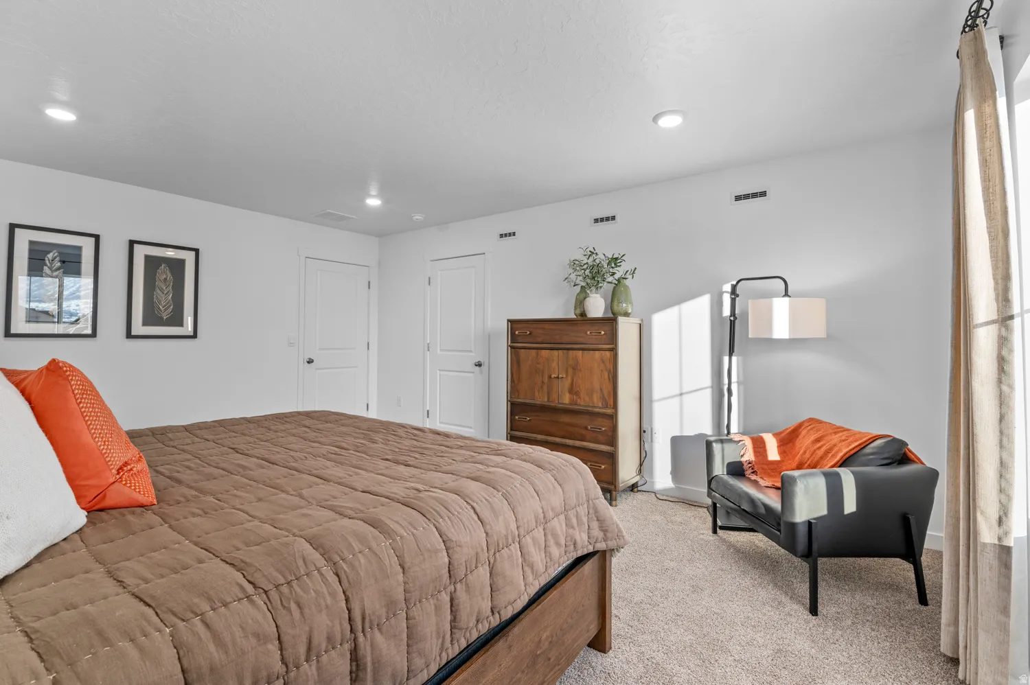 Recessed ceiling lighting, two white panel doors, light-colored carpeting, white walls, and a large window with curtain rod