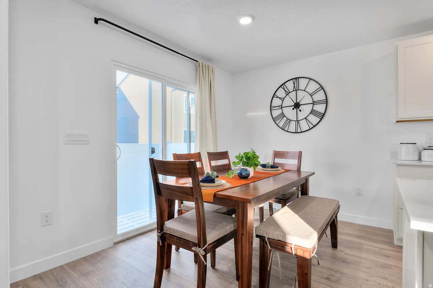 Sliding glass door, recessed lighting, wood-finish flooring, white walls, and built-in cabinetry