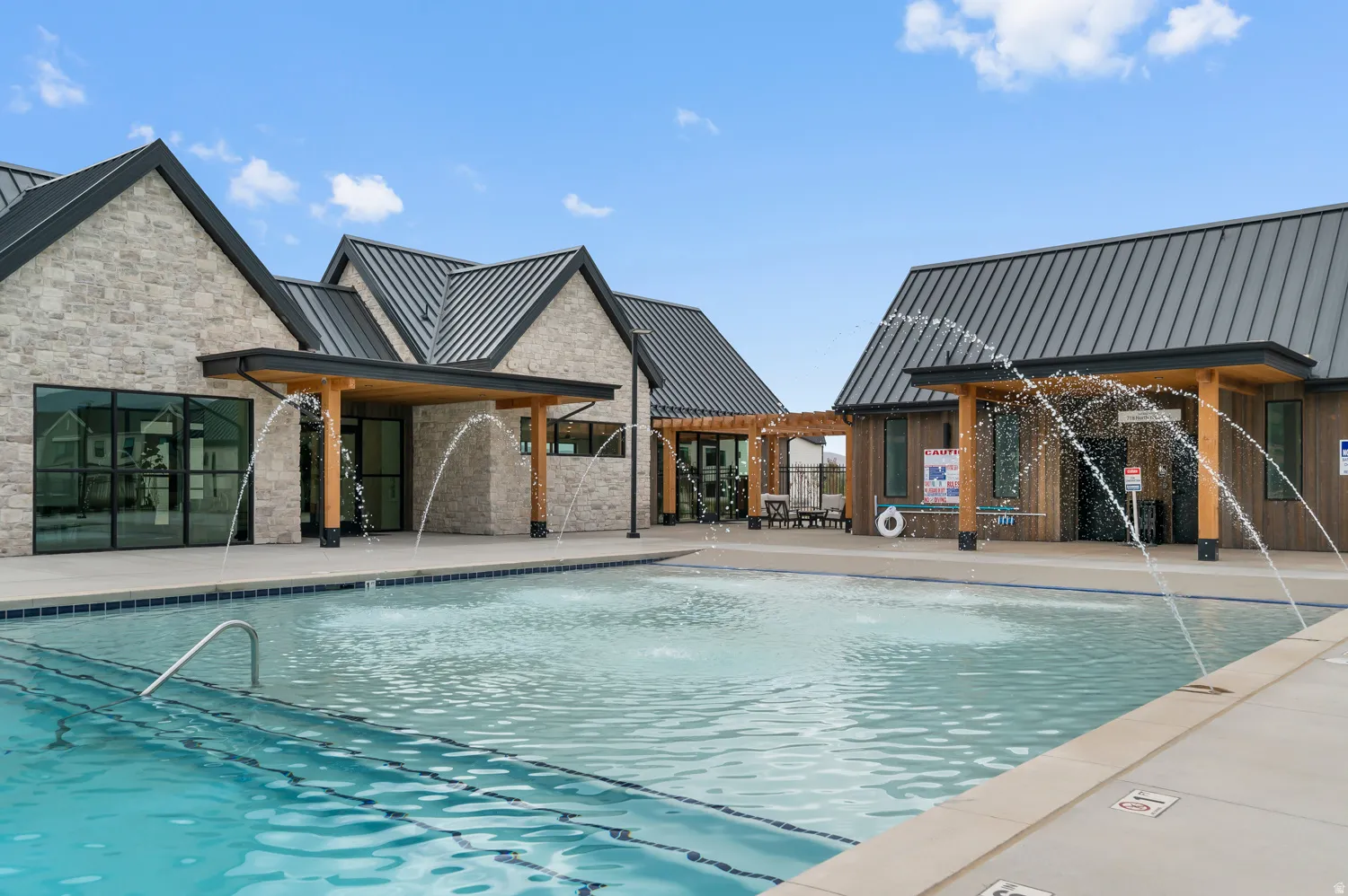 Resort-style pool with water features, stone exterior buildings, wood siding, and standing seam metal roofing