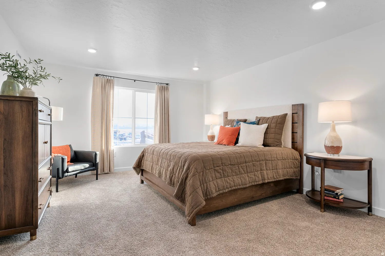 Plush carpeting, recessed lighting, and a large window with ample natural light define this bedroom