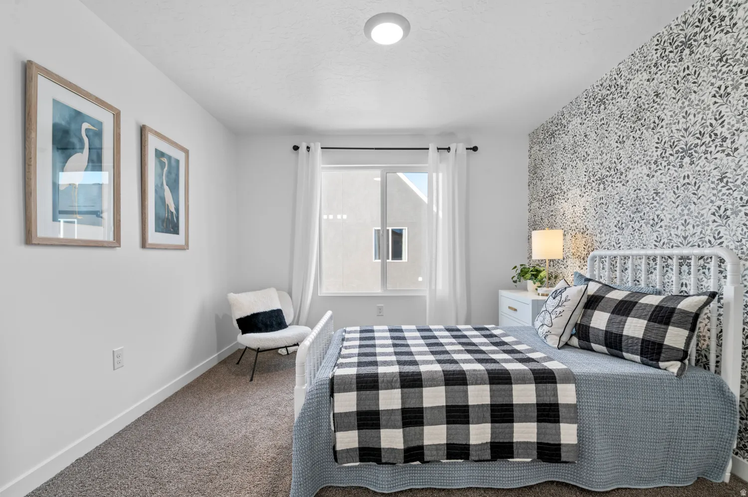 Recessed ceiling lighting, patterned accent wall, plush carpet flooring, window with sheer curtains, white window trim