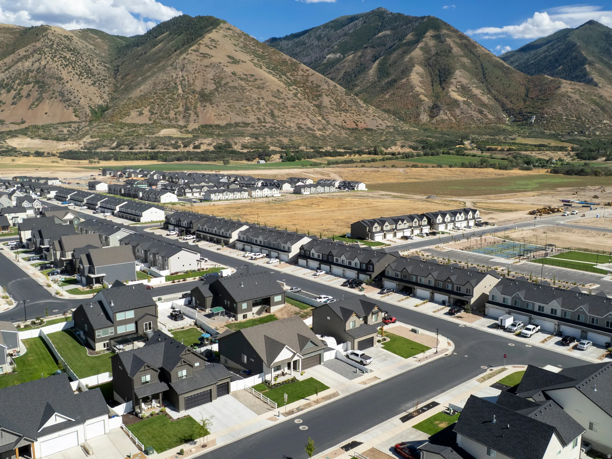 Residential development with mountain backdrop, paved streets, and a mix of detached homes and townhomes