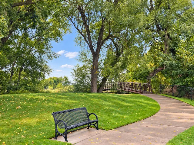 Expansive green lawn with mature trees and a paved walkway