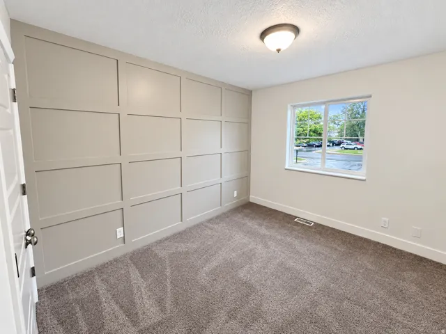 Feature wall with board-and-batten trim, neutral wall color, and plush carpet flooring