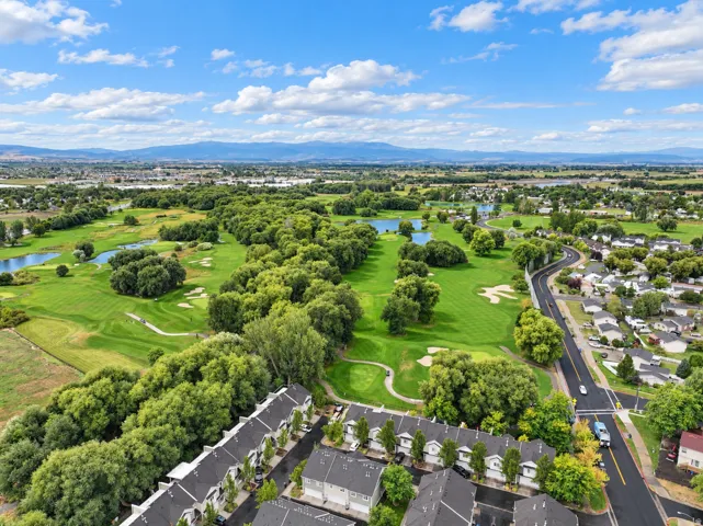 Expansive golf course with multiple water features, surrounded by mature trees and residential areas