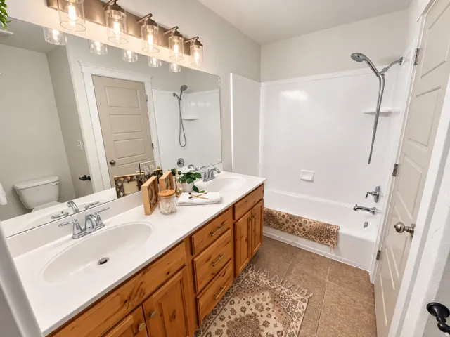 Dual vanity with wood-finish cabinetry, white countertop, and integrated sinks