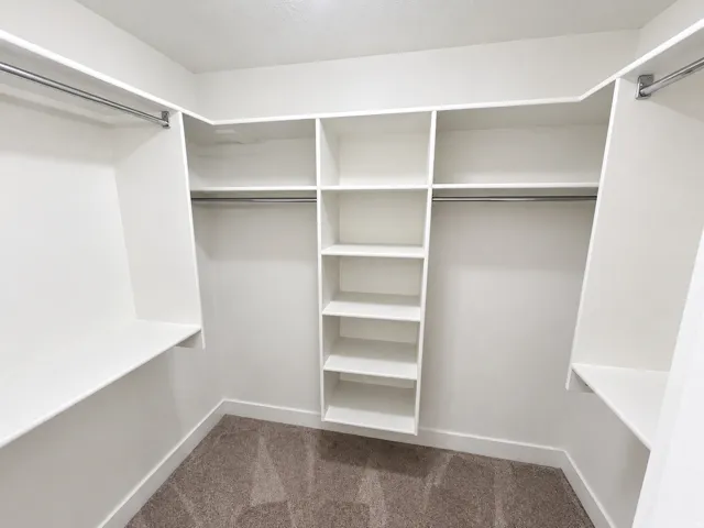 Built-in white shelving system, multiple hanging rods, corner shelving unit, and textured carpet flooring